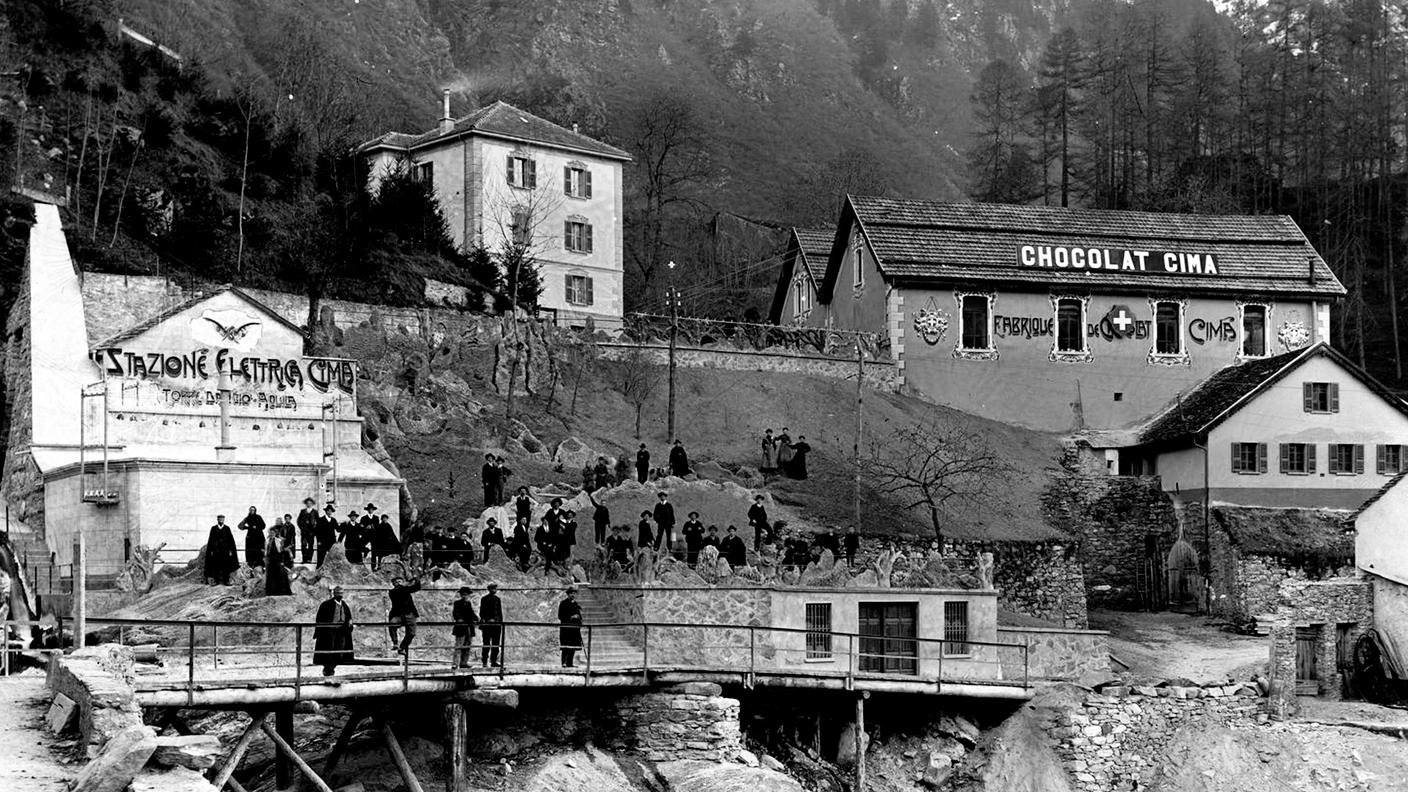 Un gruppo di uomini davanti alla stazione elettrica Cima ed alla fabbrica Cima Norma