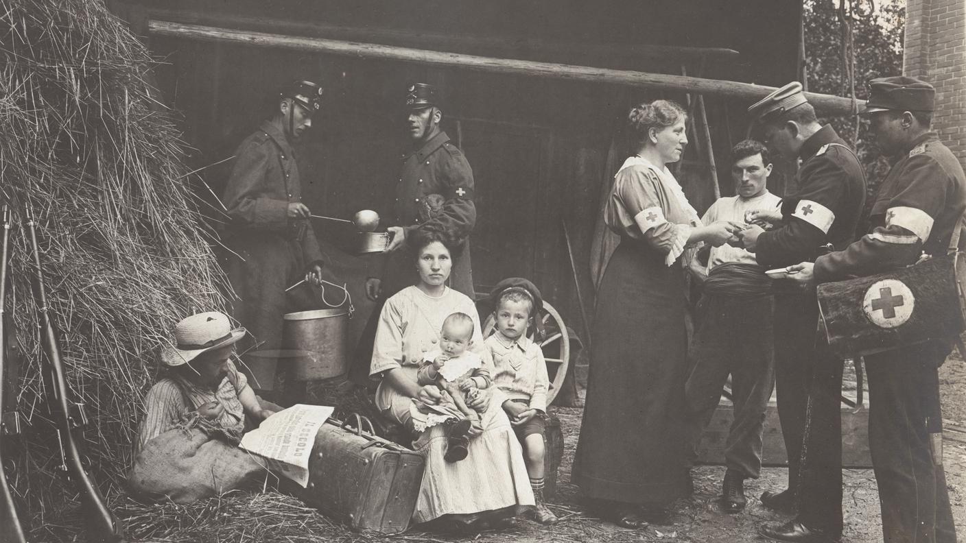 Nel 1914 migliaia di lavoratrici e lavoratori italiani attraversano la Svizzera per tornare nel proprio Paese. La Croce Rossa e l’esercito si prendono cura di coloro che sono in attesa. August Gansser, rifugiate e rifugiati provenienti dall’Alsazia, Basilea, 1914
