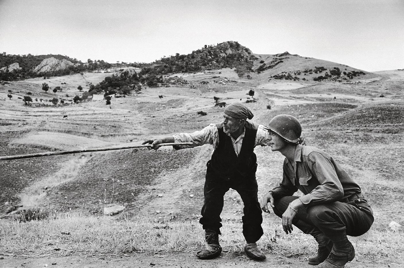 Robert Capa, Un contadino siciliano indica a un ufficiale americano la strada presa dai tedeschi, Sicilia, agosto 1943