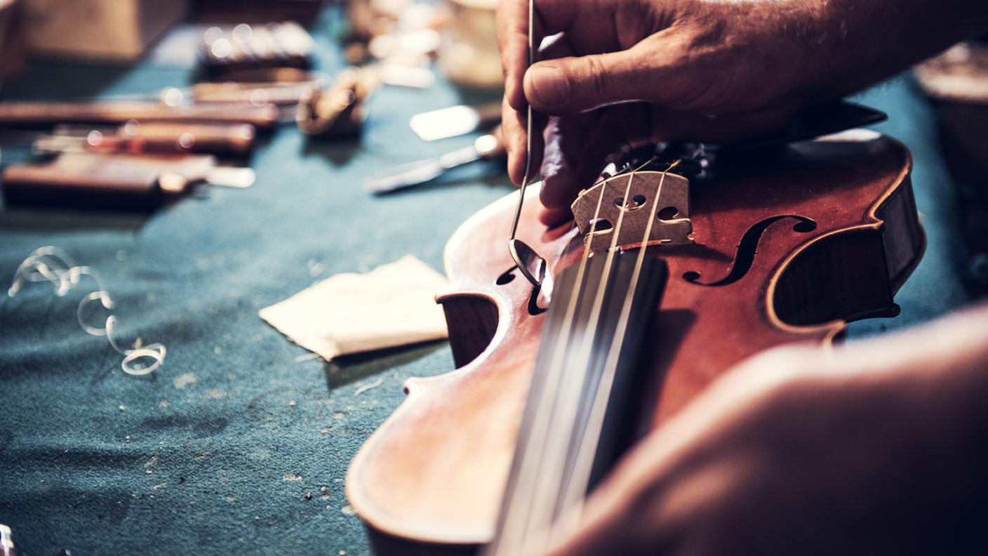 Ritratto di un artigiano che controlla il violino nel suo laboratorio di Cremona. 