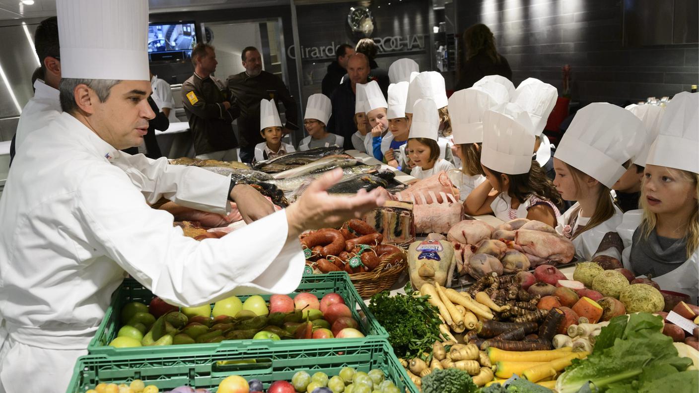 Lo chef Benoit Violier, a sinistra, mostra ogni tipo di prodotti freschi, verdure, carne e pesce agli alunni della classe di quinta elementare di Crissier durante la giornata di apertura della Settimana nazionale del Gusto, giovedì 12 settembre 2013, nella cucina del Ristorante dell'Hotel de Ville a Crissier. 