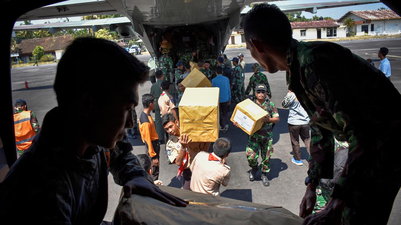 Soldati indonesiani scaricano beni di prima necessità all'aeroporto di Mataram