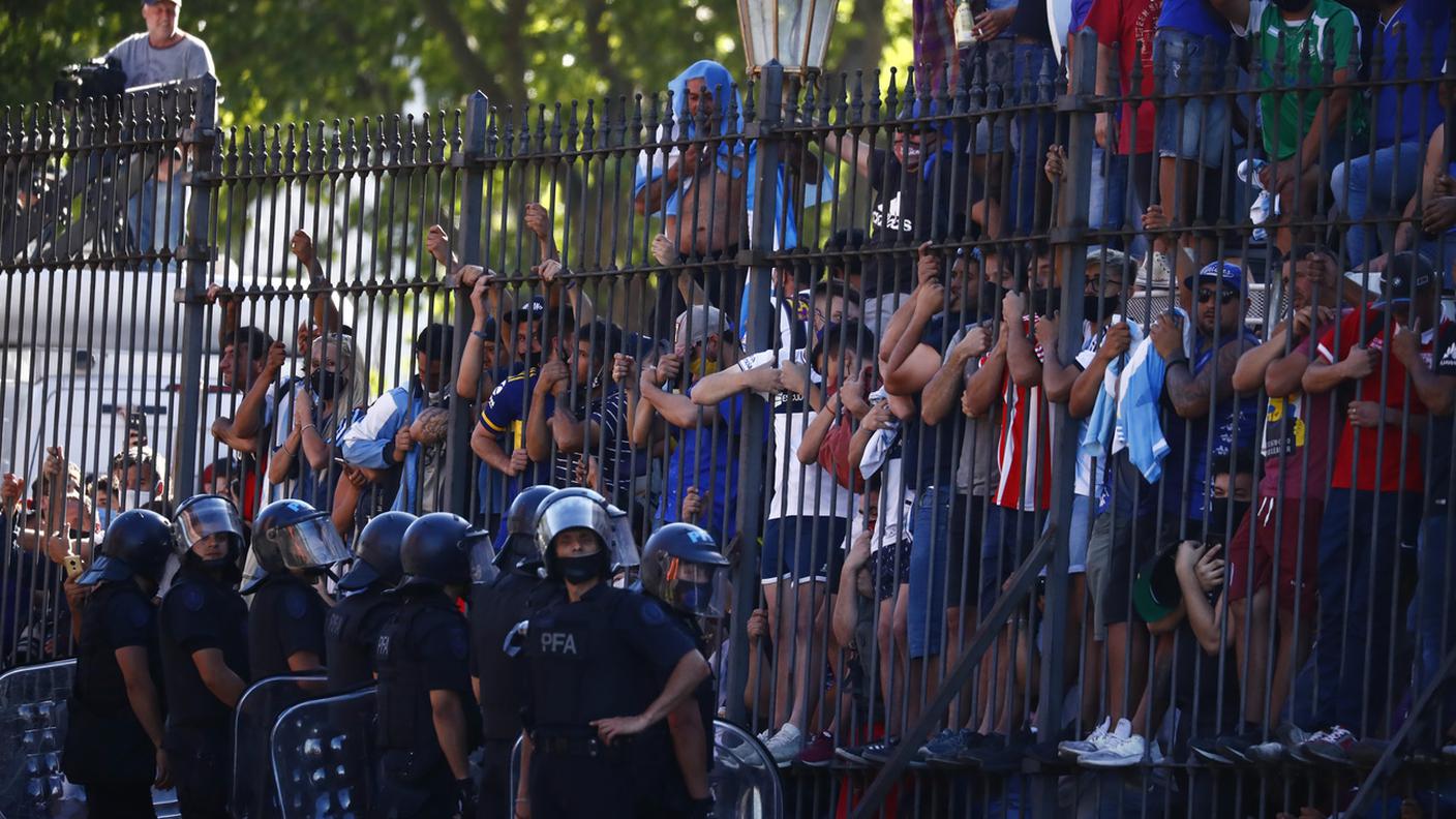 Fan in attesa di vedere il passaggio del veicolo funebre a Buenos Aires