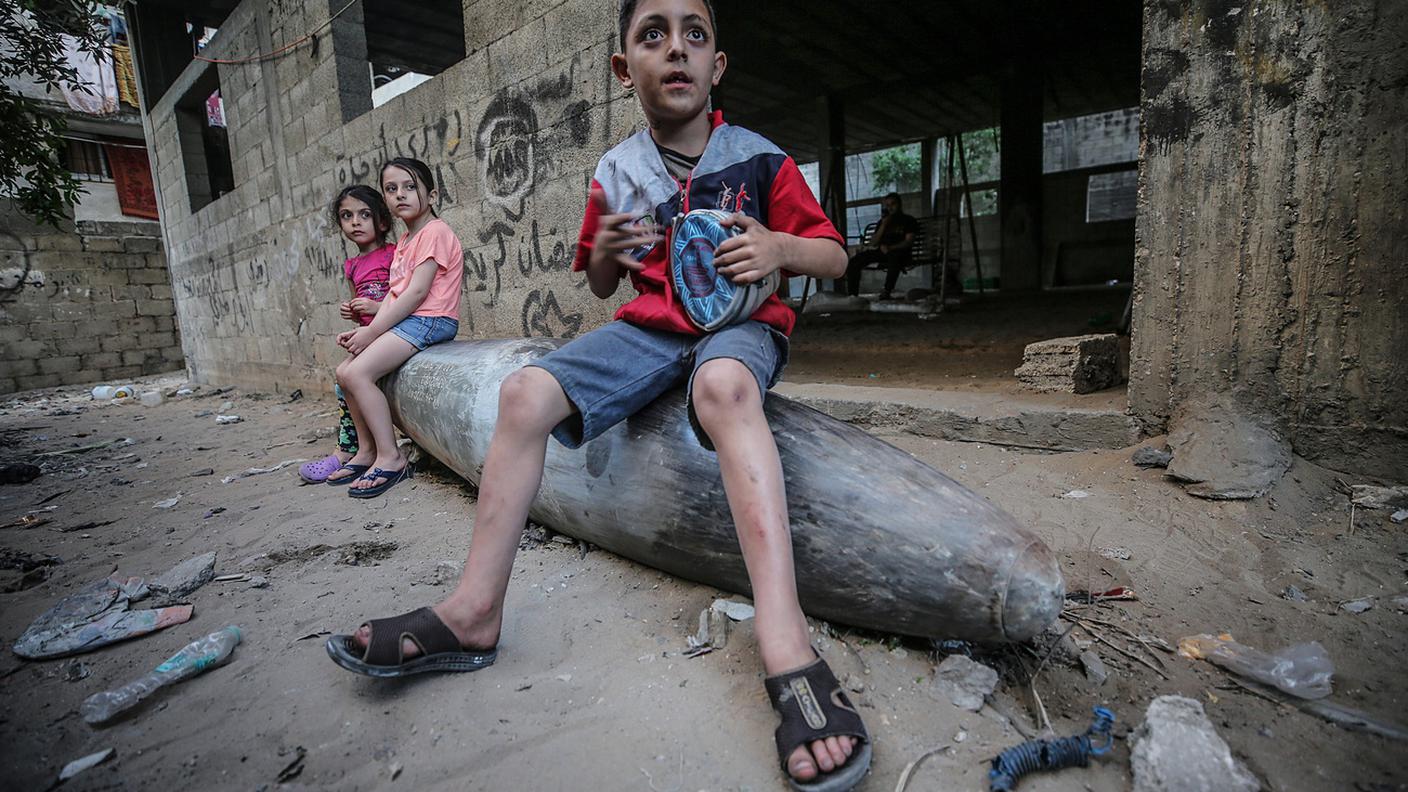 Bambini palestinesi siedono su un missile inesploso a Gaza city il 19 maggio