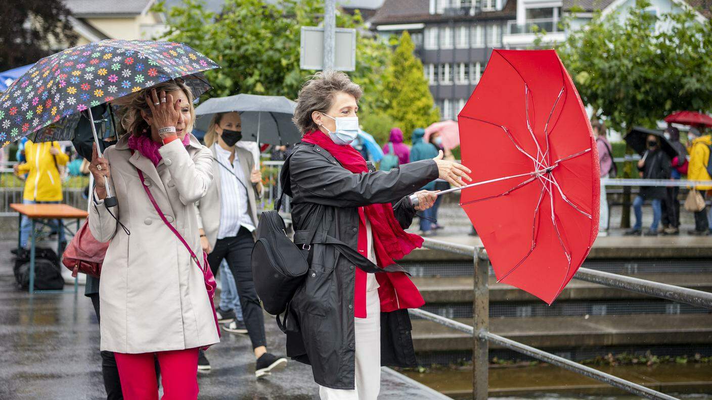 1° agosto bagnato e ventoso per Simonetta Sommaruga, in difficoltà con l'ombrello