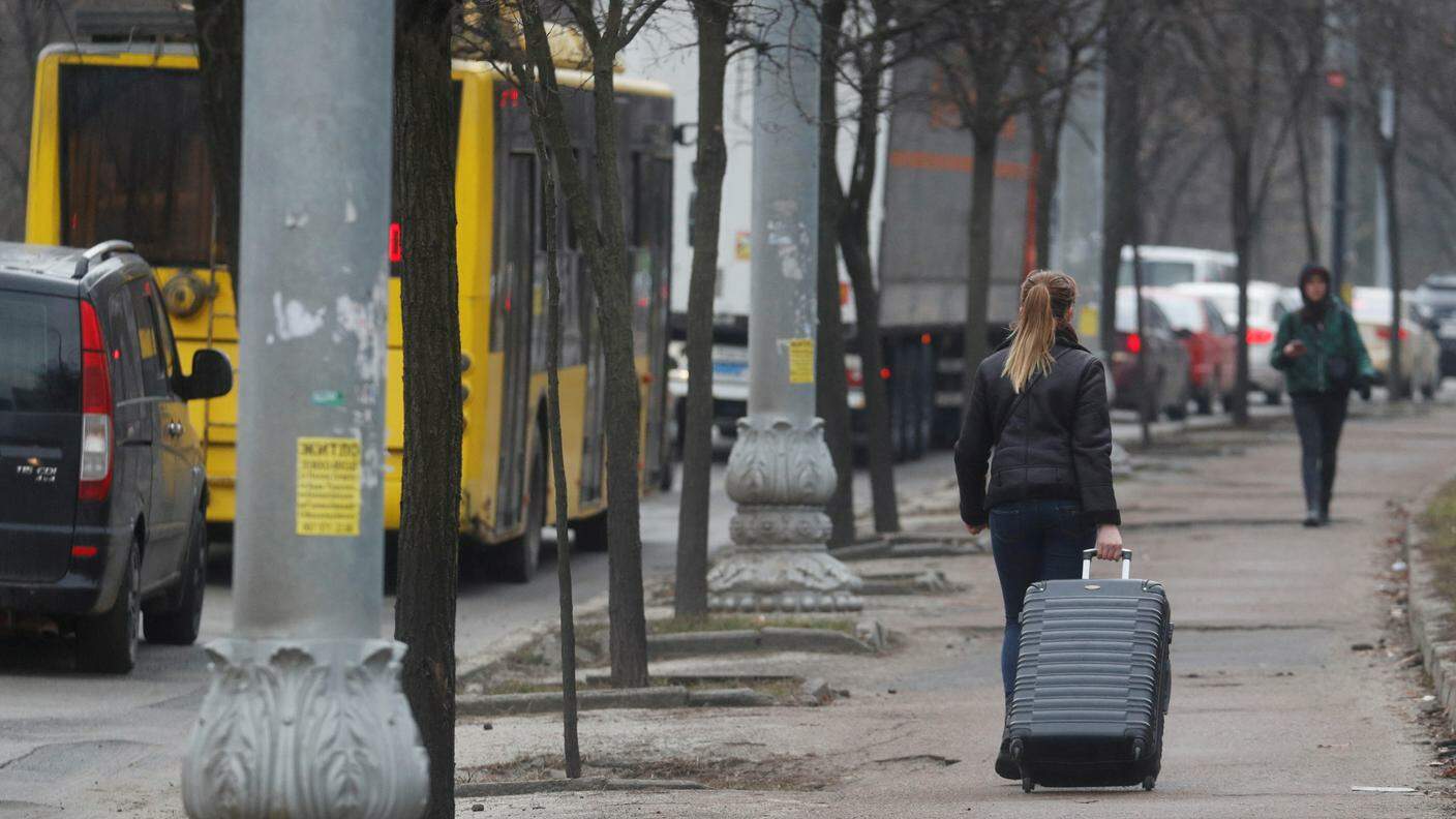 Diverse automobili ed una donna con una valigia lasciano Kiev