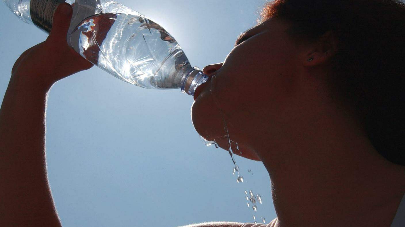Donna che beve dell'acqua durante un'ondata di caldo