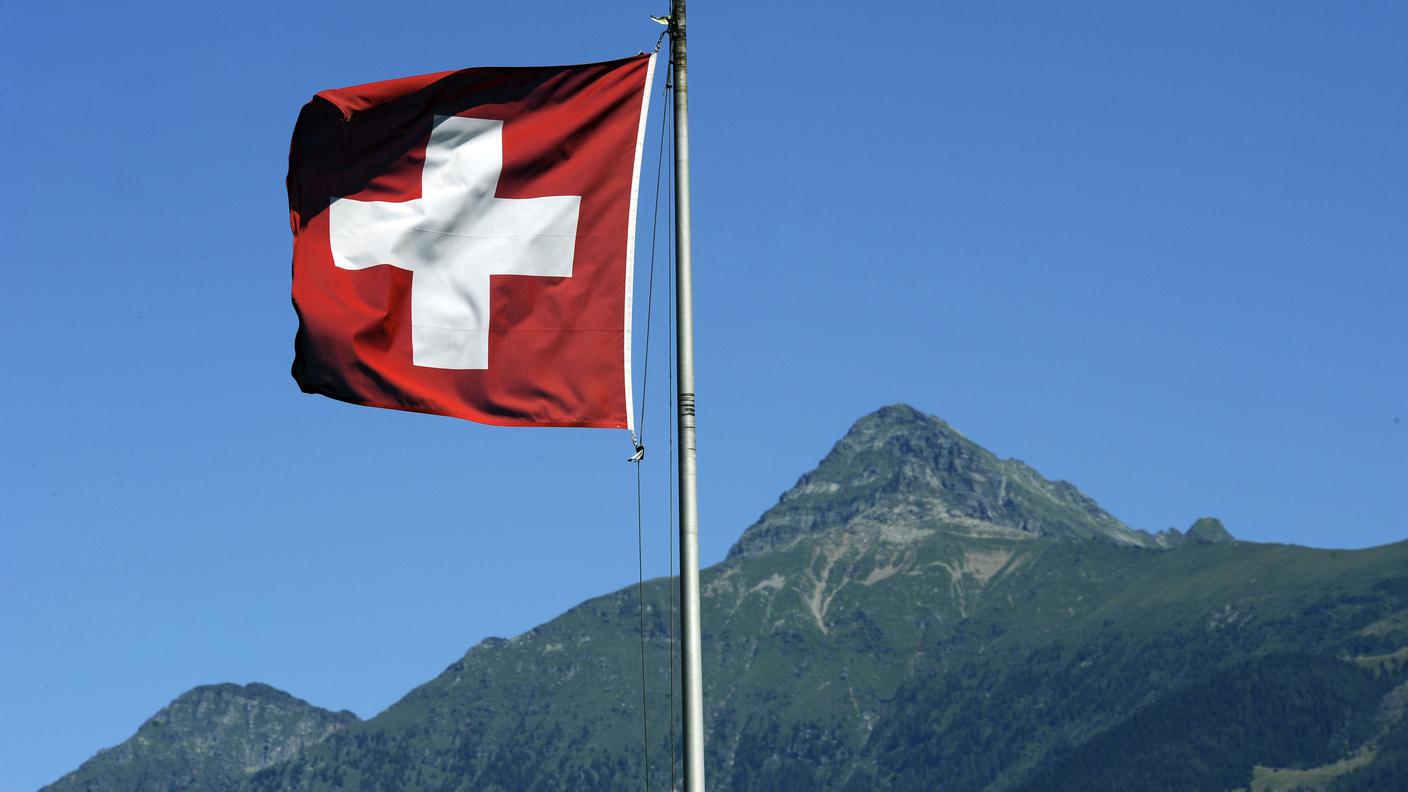 La bandiera svizzera sventola al vento e sullo sfondo il Pizzo di Claro