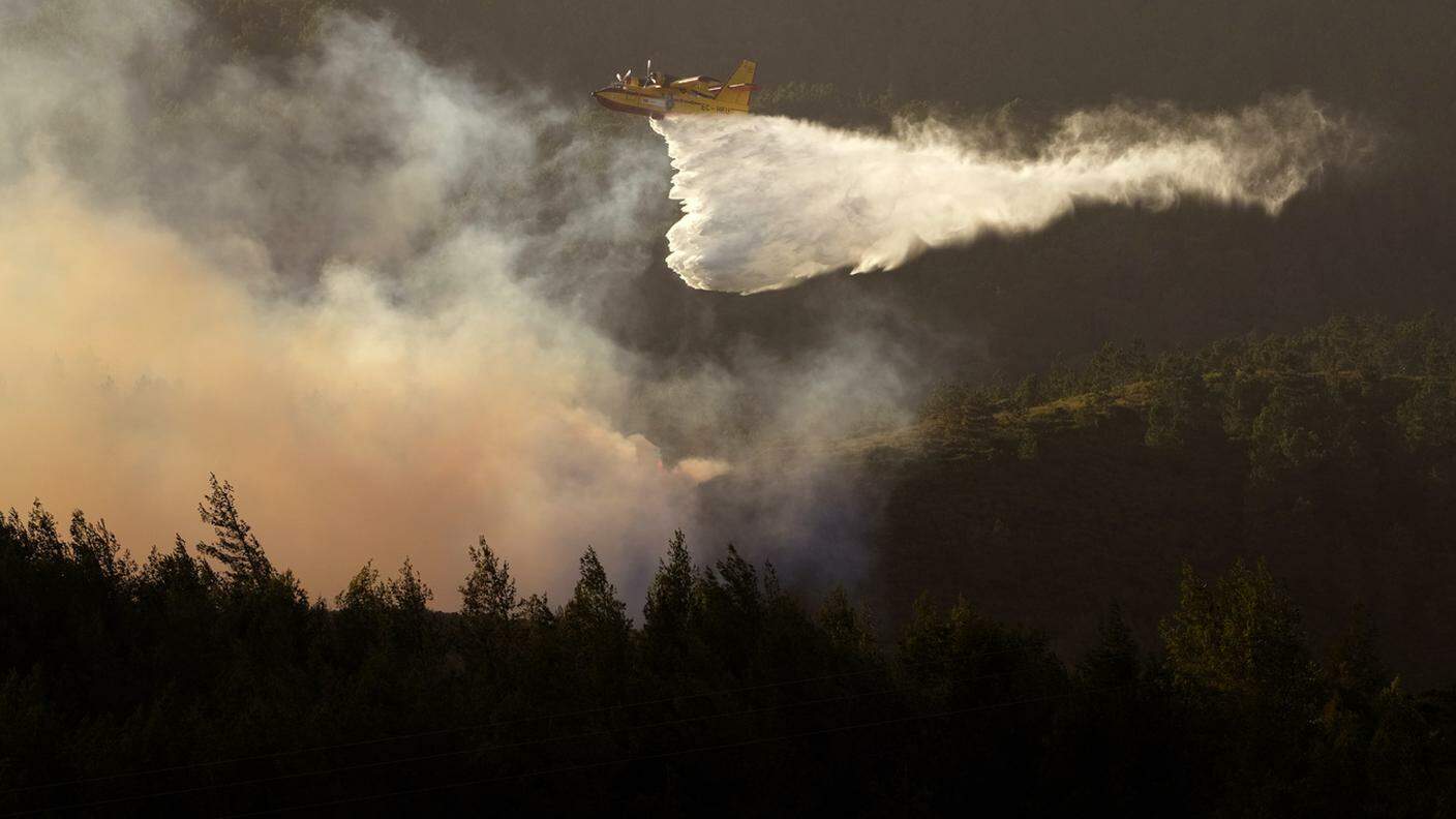 Un canadair impegnato a spegnere le fiamme nei boschi vicino a Lisbona