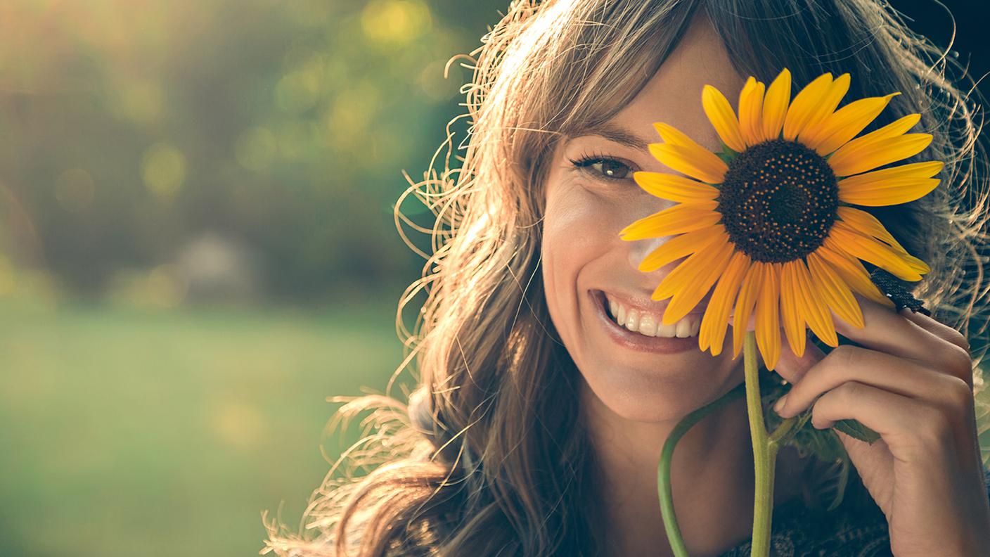 Nel parco che copre il viso con girasole, donna, ecologia, felicità