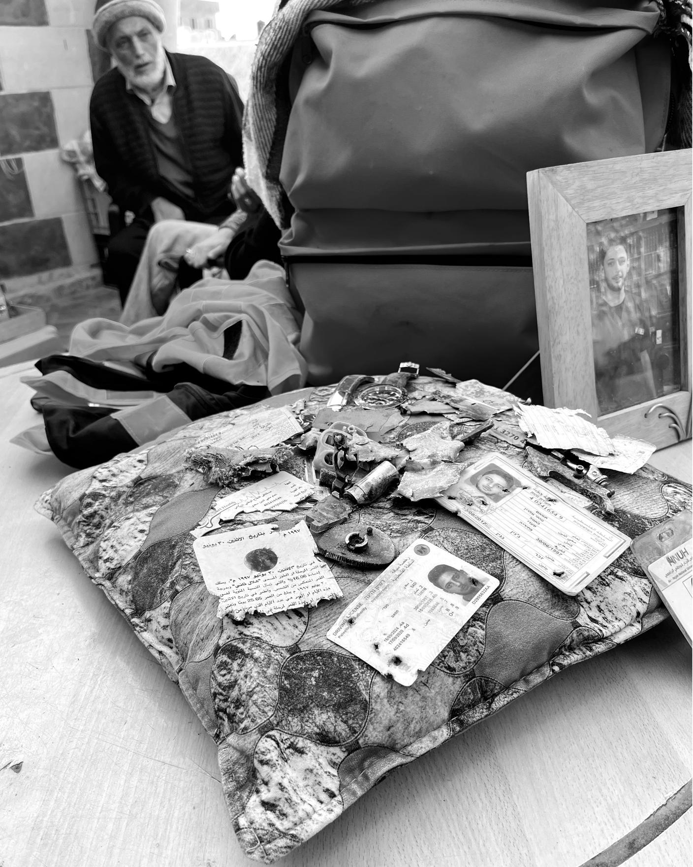 FOTO 13 -  Documenti ed effetti personali di Tamam al-Sadi, l'infermiere 28enne ucciso da un drone israeliano, sullo sfondo suo papà (Emiliano Bos - RSI).JPEG