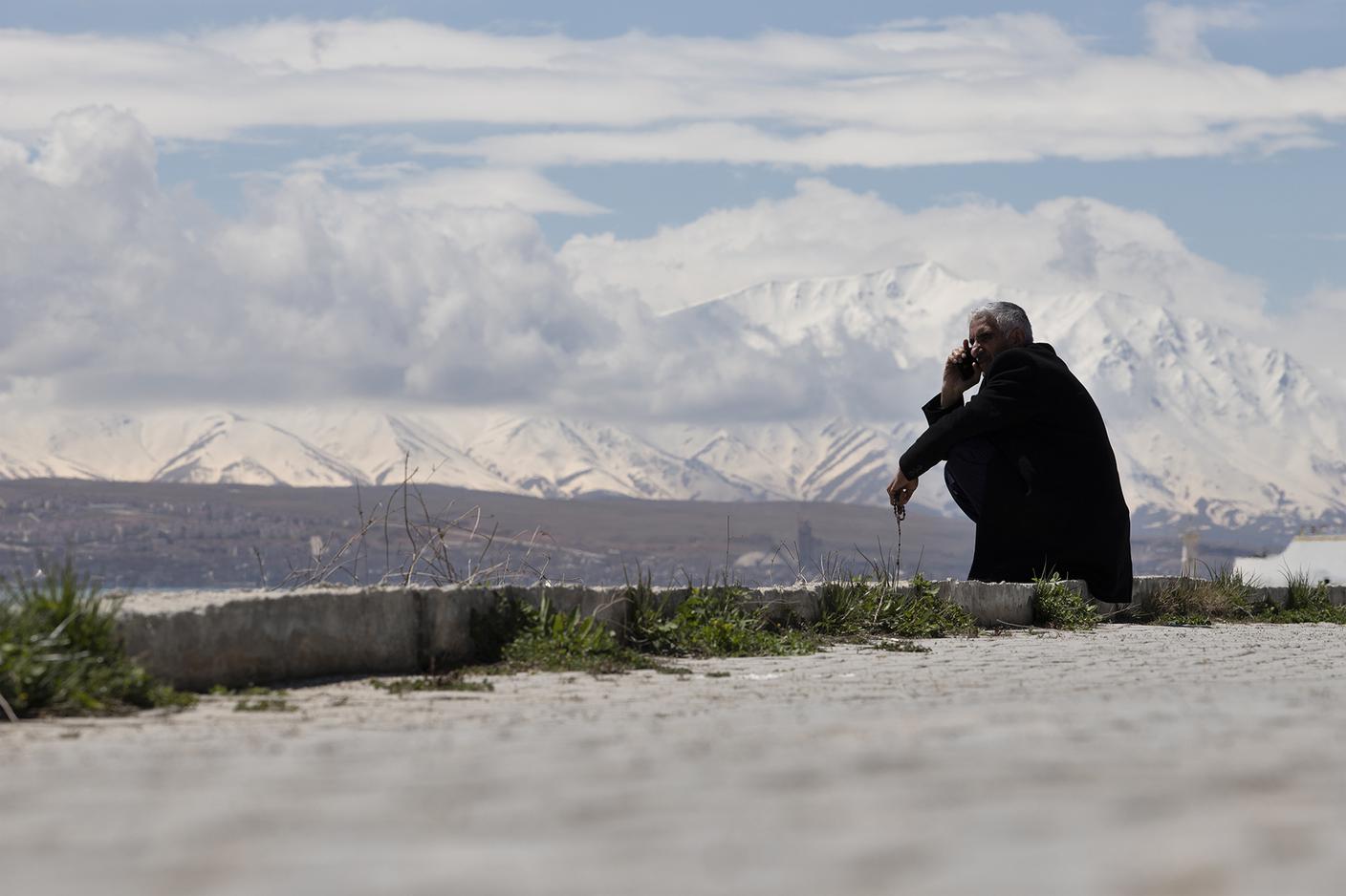 Sulle rive del Lago di Van, un anziano curdo accovacciato osserva l’acqua immobile.