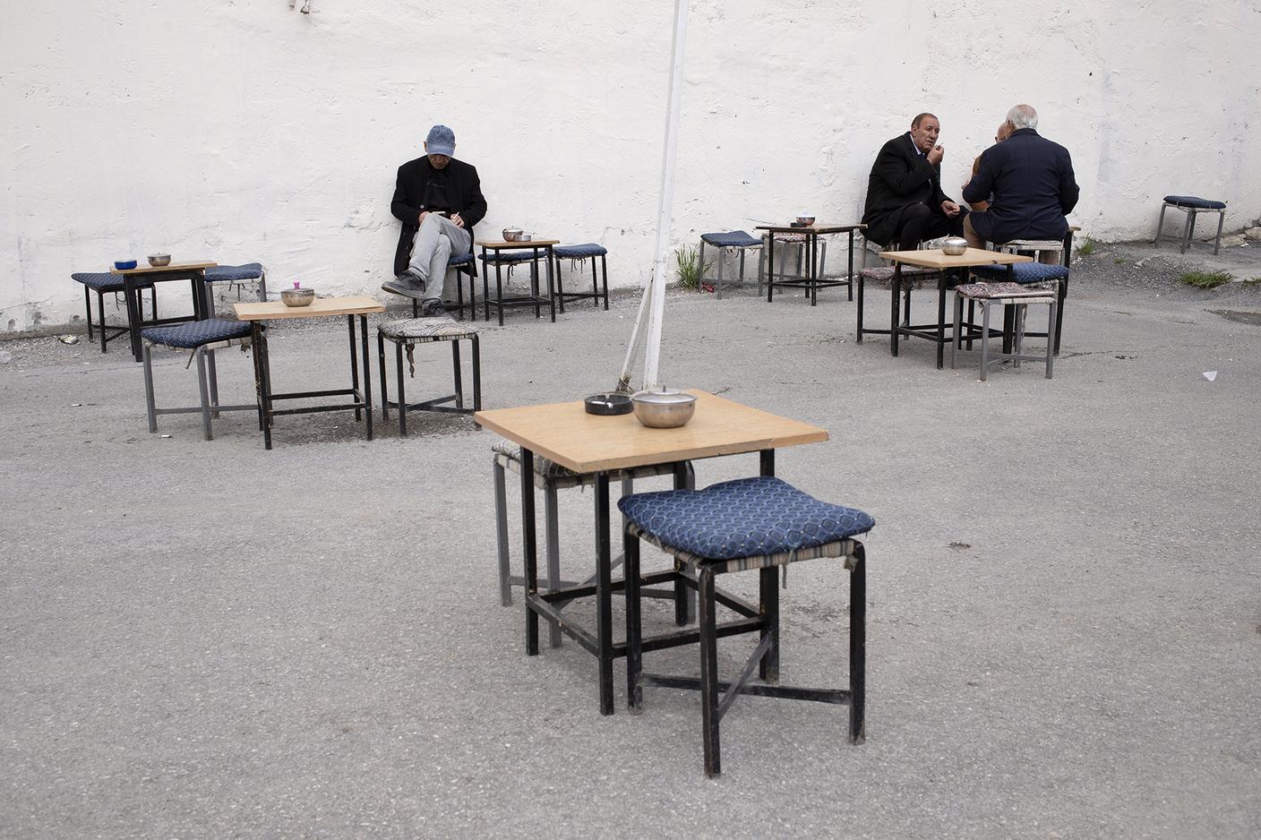 Uomini curdi fumano e chiacchierano nel cortile di una sala da tè.