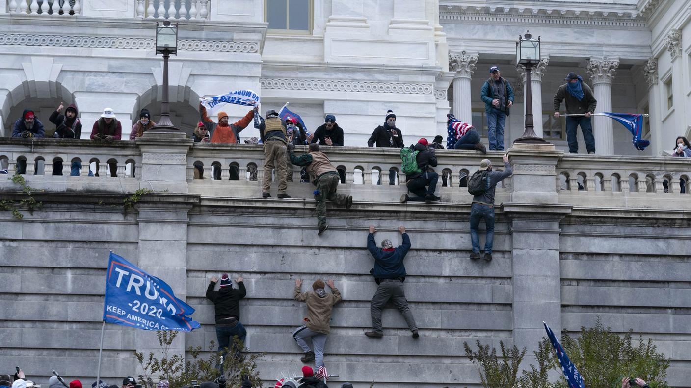 I sostenitori di Donald Trump si arrampicano sul lato occidentale del Campidoglio degli Stati Uniti, mercoledì 6 gennaio 2021, a Washington.
