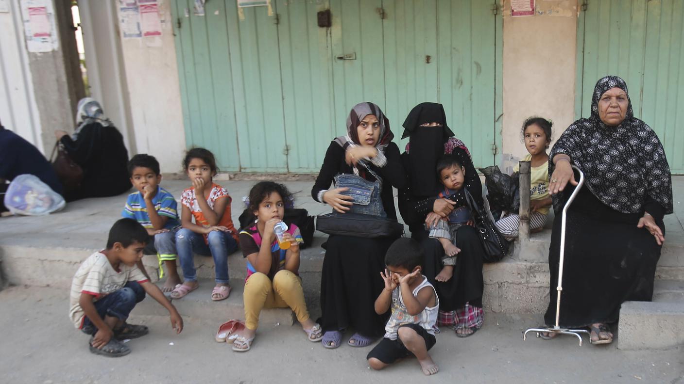 Una famiglia siede sulla strada dopo aver abbandonato le proprie abitazioni, a Rafah