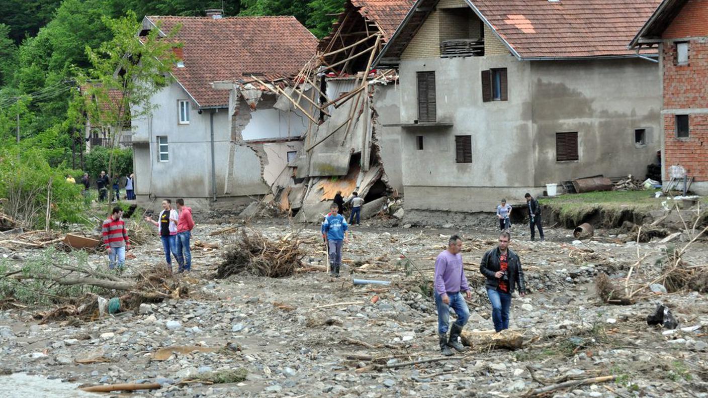 Cittadini di Krupanj, in Serbia, si muovono tra le case distrutte (keystone).jpg