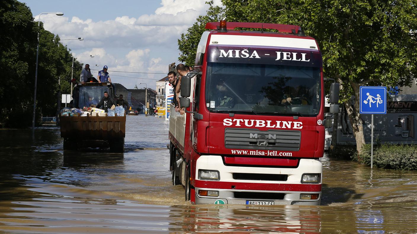 Un camion carico di persone si muove a fatica per le strade allagate in Serbia (keystone).jpg