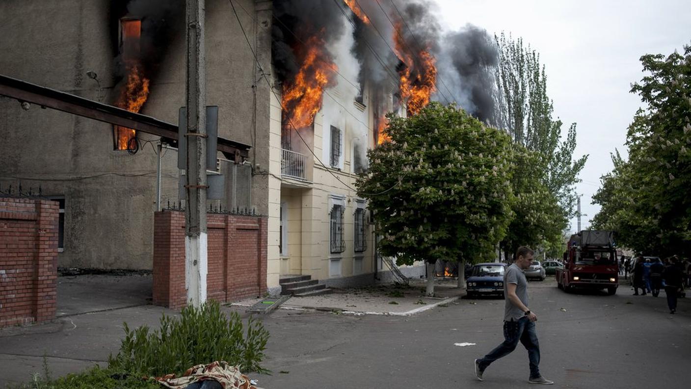 Il corpo del poliziotto ucciso giace accanto alla stazione della polizia di Mariupol in preda alle fiamme