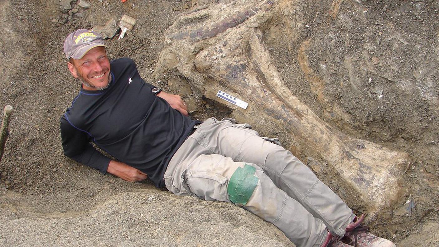 Uno degli scopritori accanto a una tibia del colosso