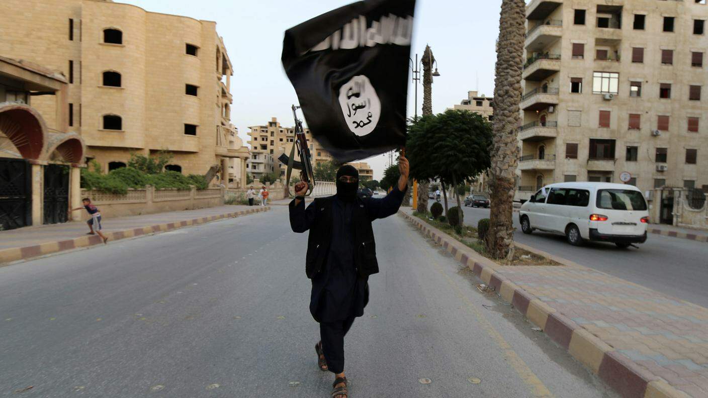 Un membro dell'IS con la bandiera dell'autoproclamato Stato islamico
