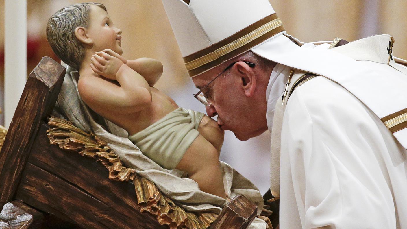 Il Papa bacia la statuetta del Bambin Gesù durante la messa di Natale
