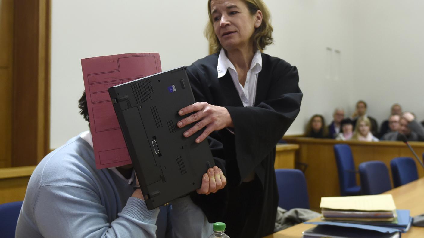 L'infermiere, in aula, si copre il volto con l'aiuto della sua legale