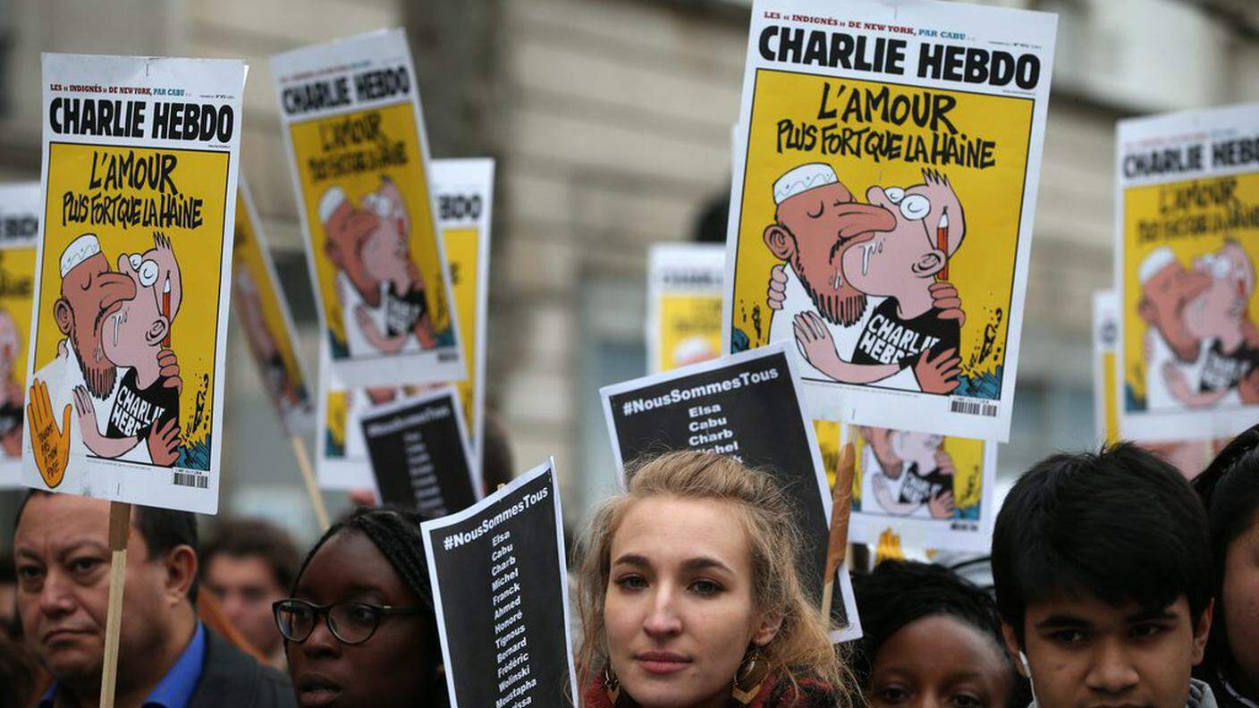 Manifestanti con manifestanti raffiguranti una famosa vignetta di Charlie Hebdo