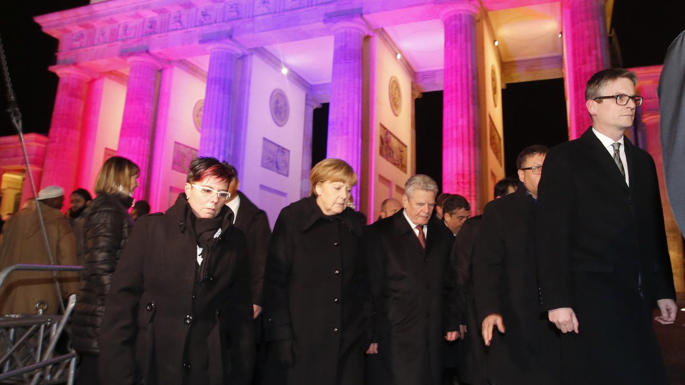 Merkel e Gauck (al centro) camminano dalla porta di Brandenurgo verso l'ambasciata francese
