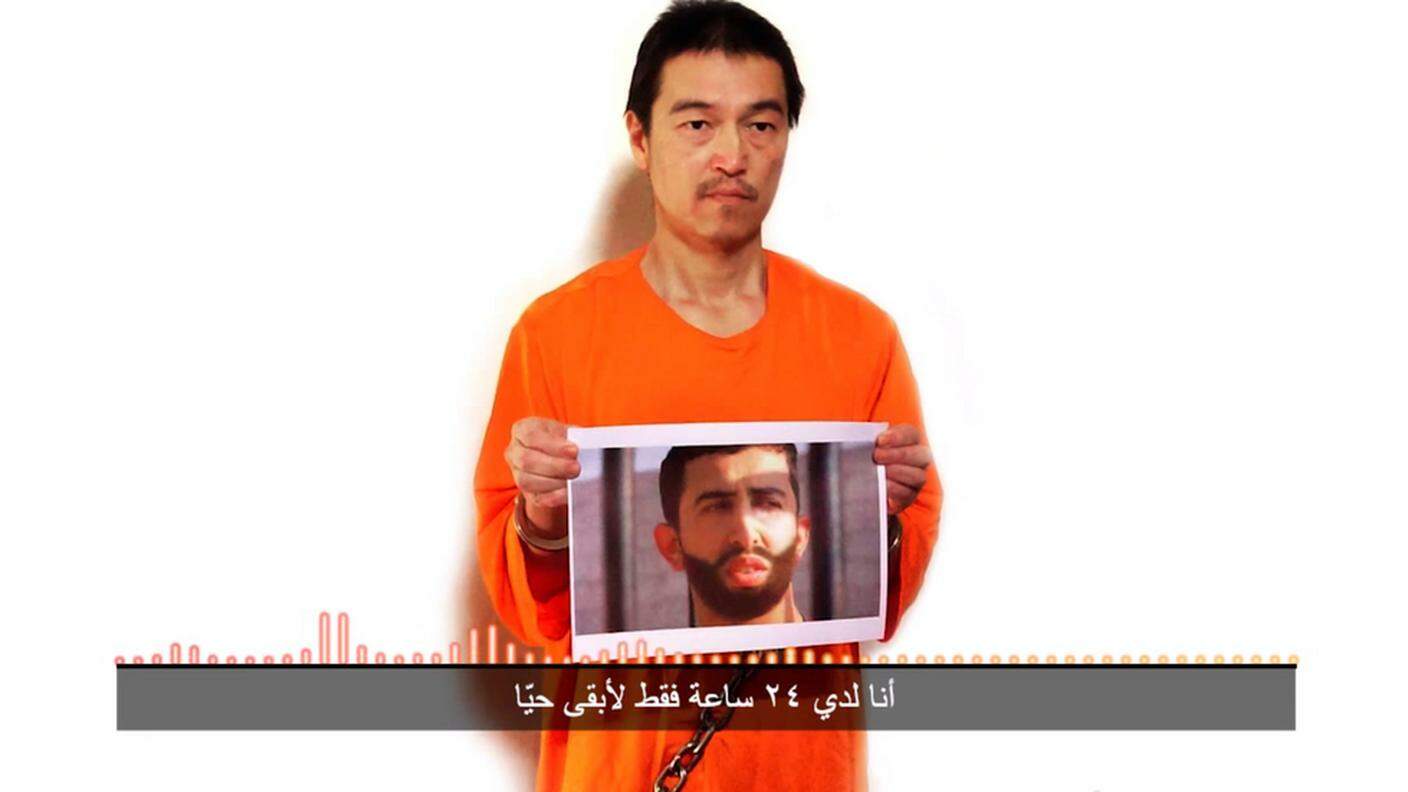L'ostaggio nipponico nell'ultimo video dell'IS con una foto del pilota giordano che gli estremisti dichiarano avere in ostaggio