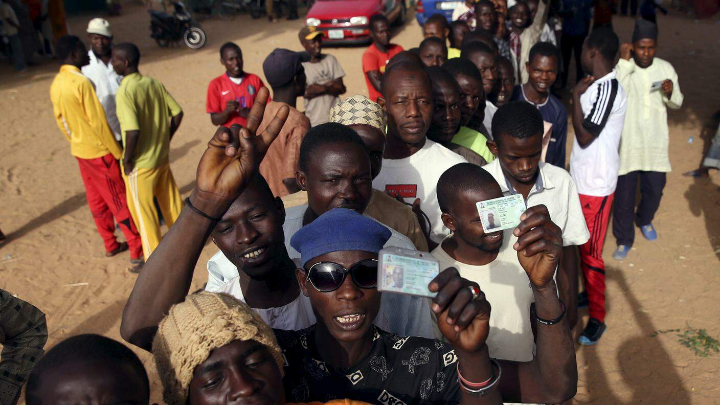 Cittadini nigeriani mostrano la carta d'identita mentre sono in fila per votare
