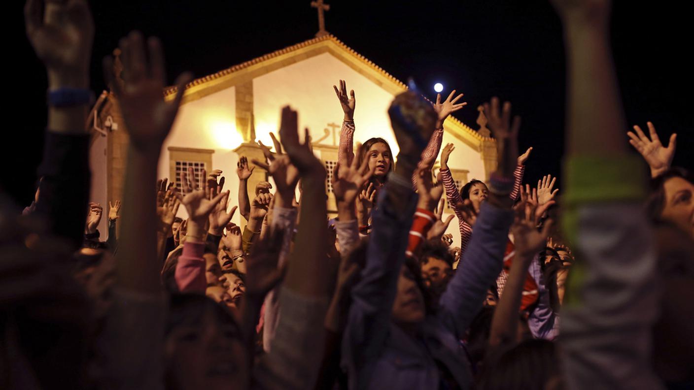 I fedeli elevano le mani all'esterno di una chiesa a Idanha-a-Nova, in Portogallo