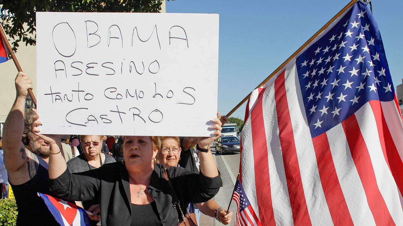 "Obama: assassino come i Castro", nel cartello di un'esule cubana durante una protesta a Miami contro le aperture del capo della Casa Bianca