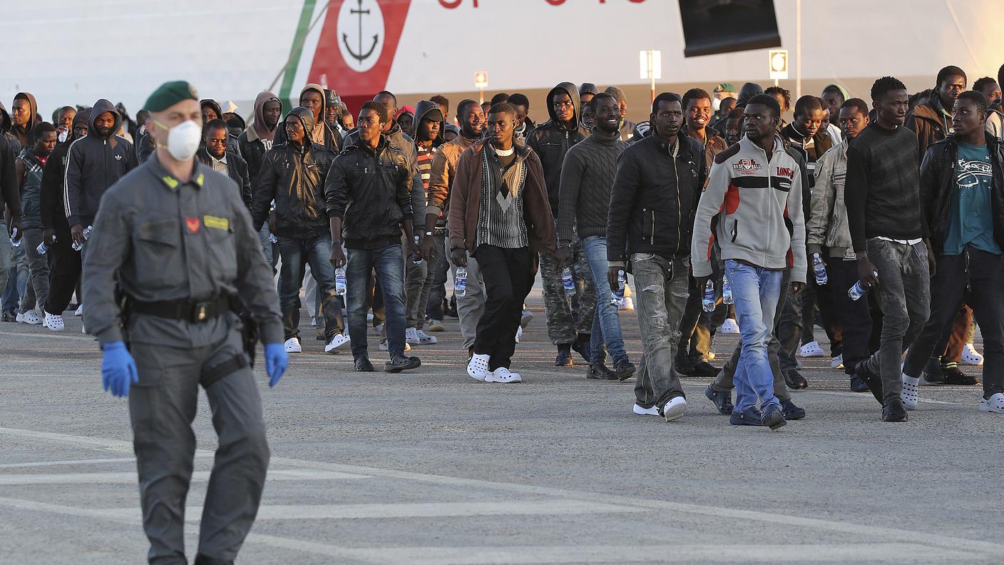Un gruppo di migranti sbarca da una nave della guardia costiera italiana