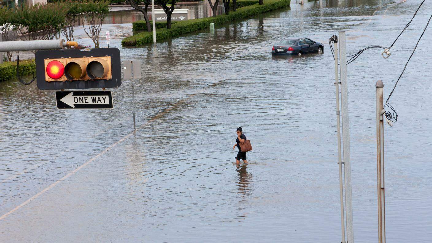 Una donna attraversa una strada di Houston totalmente allagata