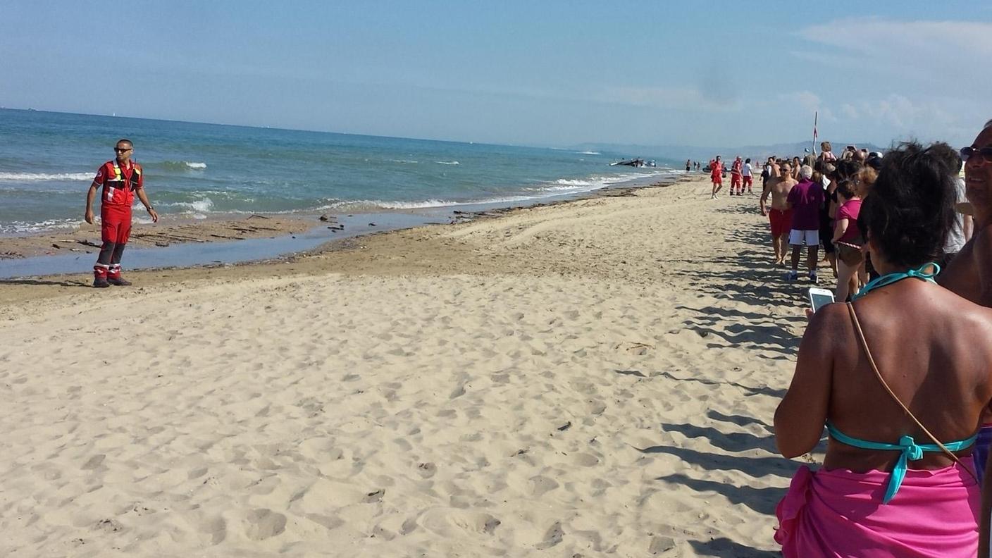 Le persone in spiaggia osservano attoniti le operazioni di recupero