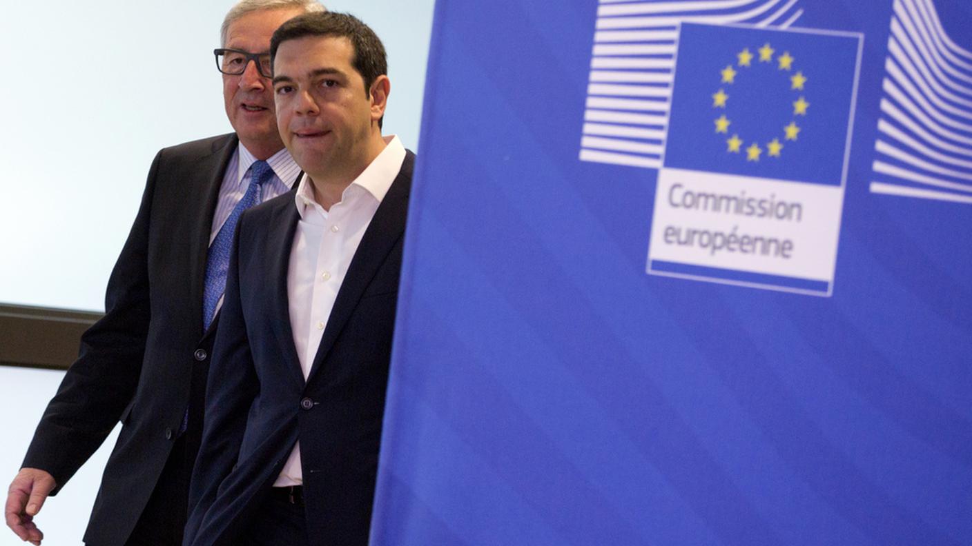 Il premier greco Tsipras e, alle sue spalle, il presidente della Commissione UE