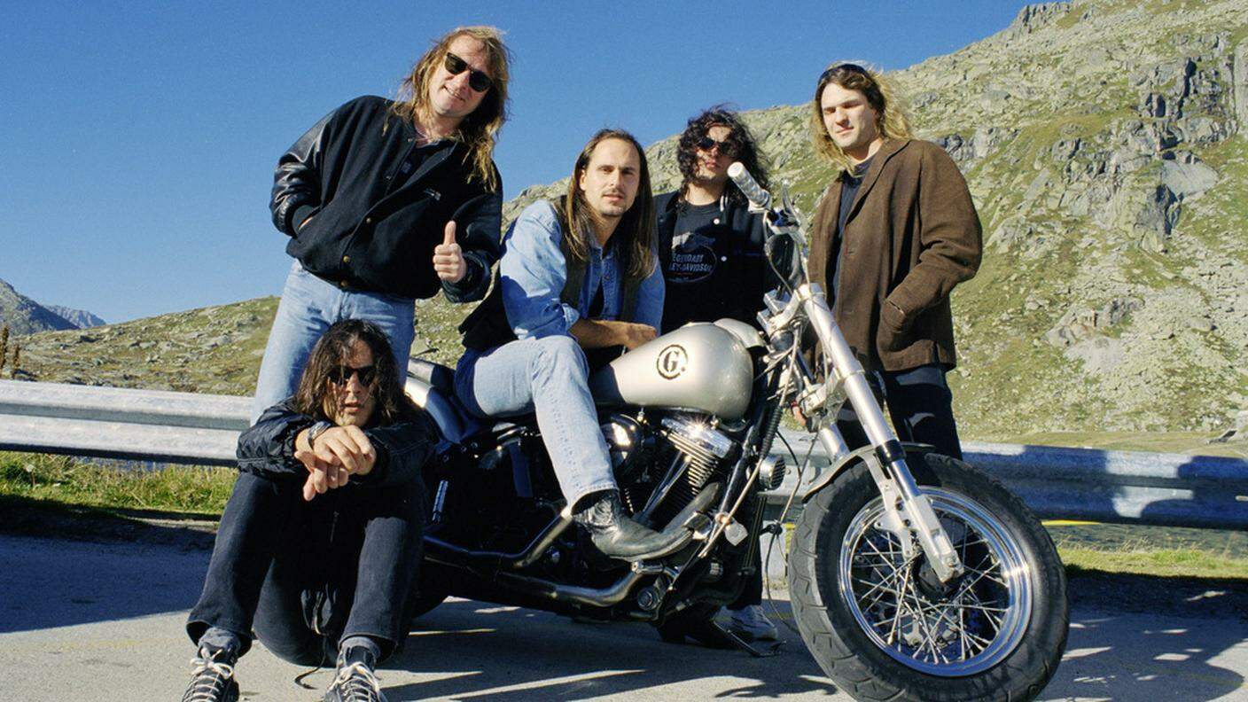 La band nel 1997 riunita vicino a una moto. In sella c'è Steve Lee