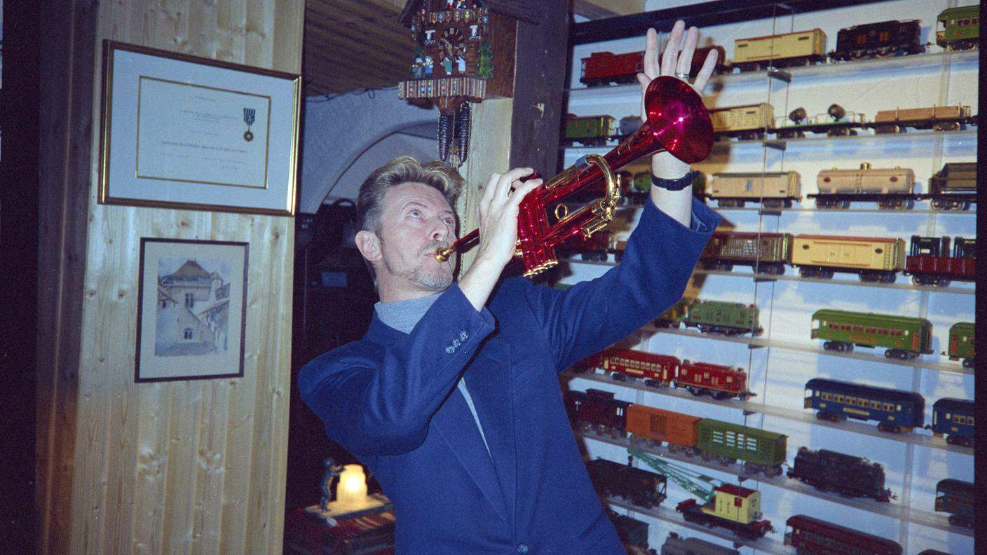 David Bowie con la tromba di Miles Davis davanti a modellini ferroviari nello chalet Le Picotin a Caux nel 1995