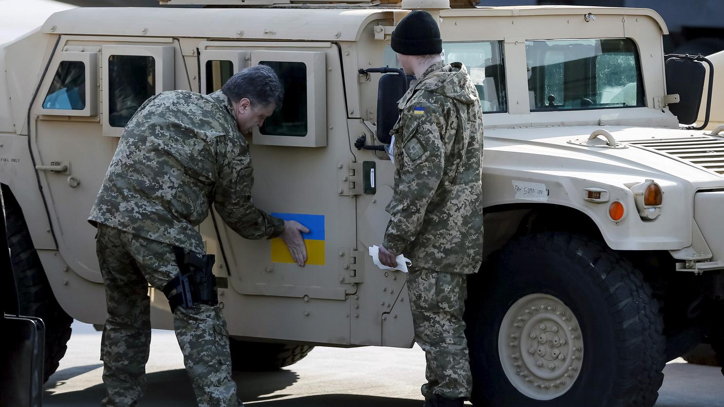 Il presidente Petro Poroshenko incolla una bandiera ucraina su un Humvee