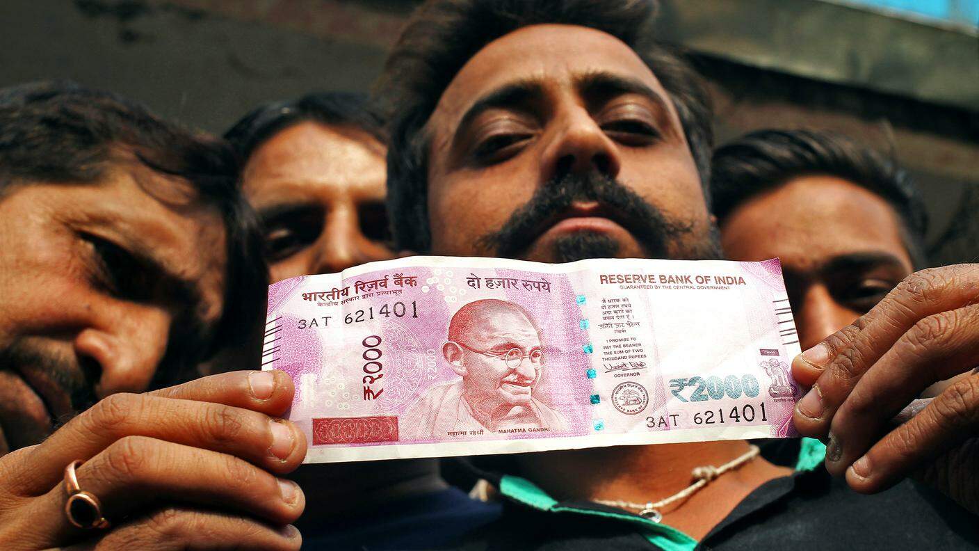 Un uomo esibisce la nuova banconota da 2'000 rupie