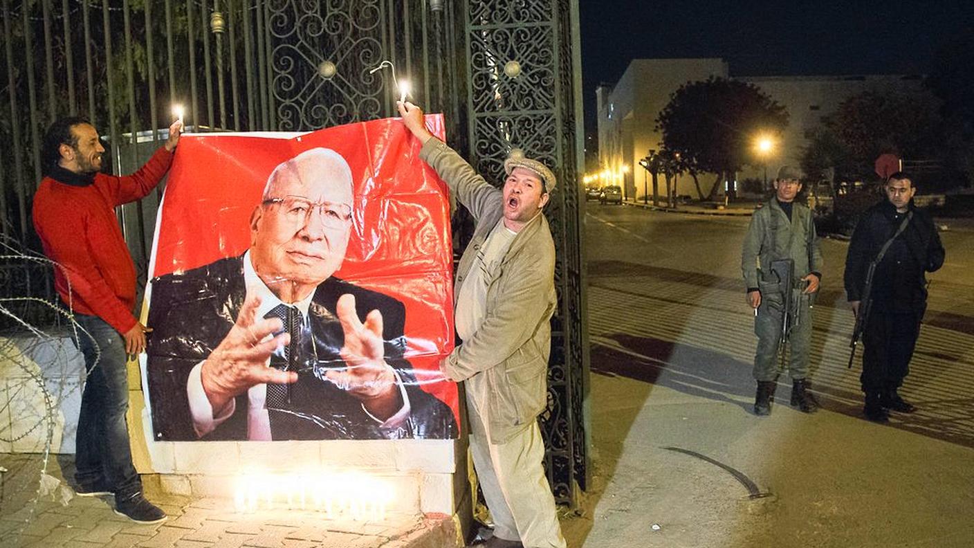 Un gruppo di persone appende un manifesto del presidente Béji Caïd Essebsi