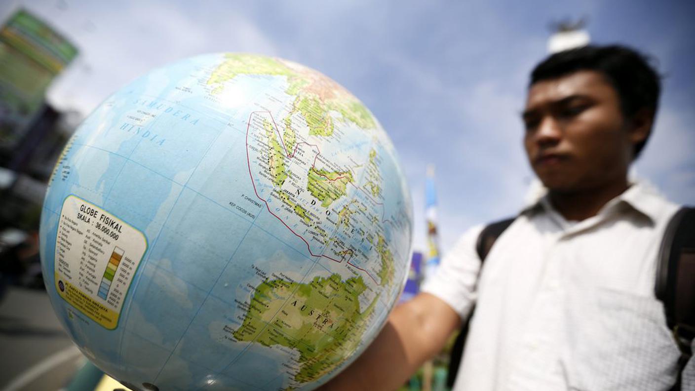 Un manifestante tiene in mano un globo terrestre durante una manifestazione a banda Aceh, in Indonesia (colpita dallo tsunami 10 anni fa)