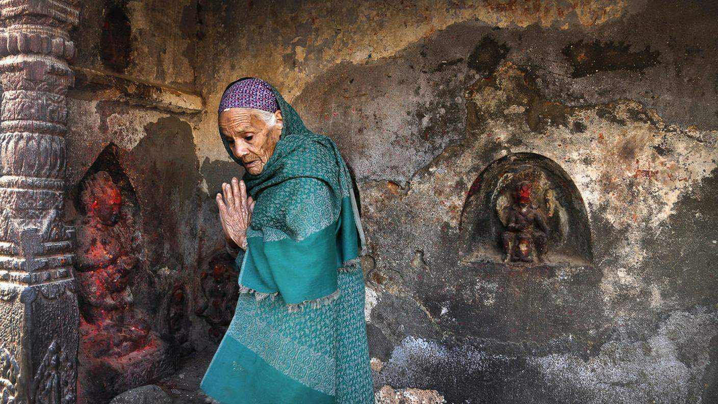 Una donna prega in un tempio danneggiato dal sisma