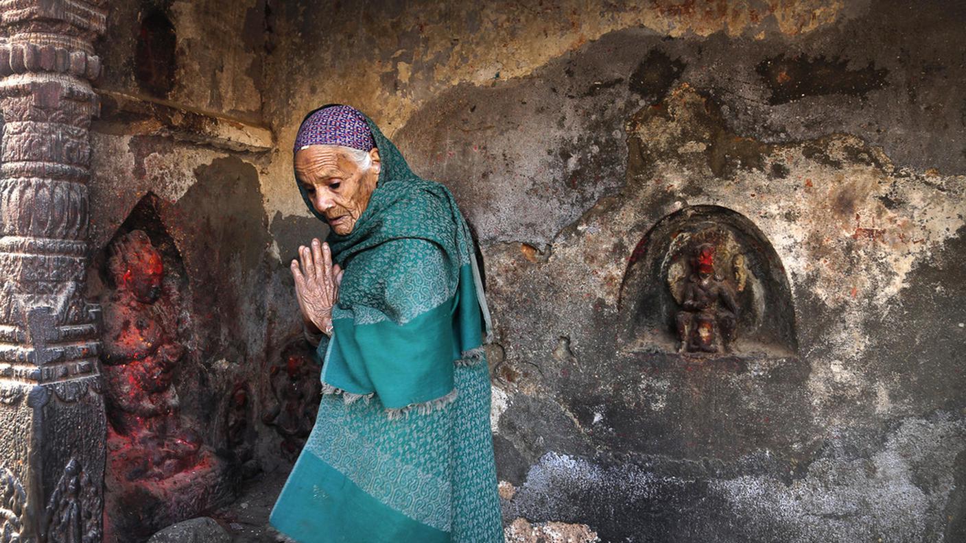 Una donna prega in un tempio danneggiato dal sisma