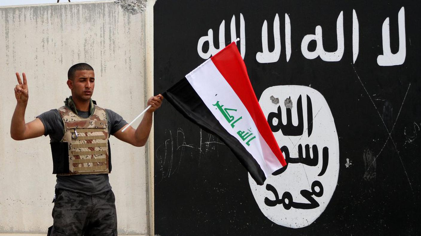 Un soldato iracheno davanti alla bandiera dell'IS