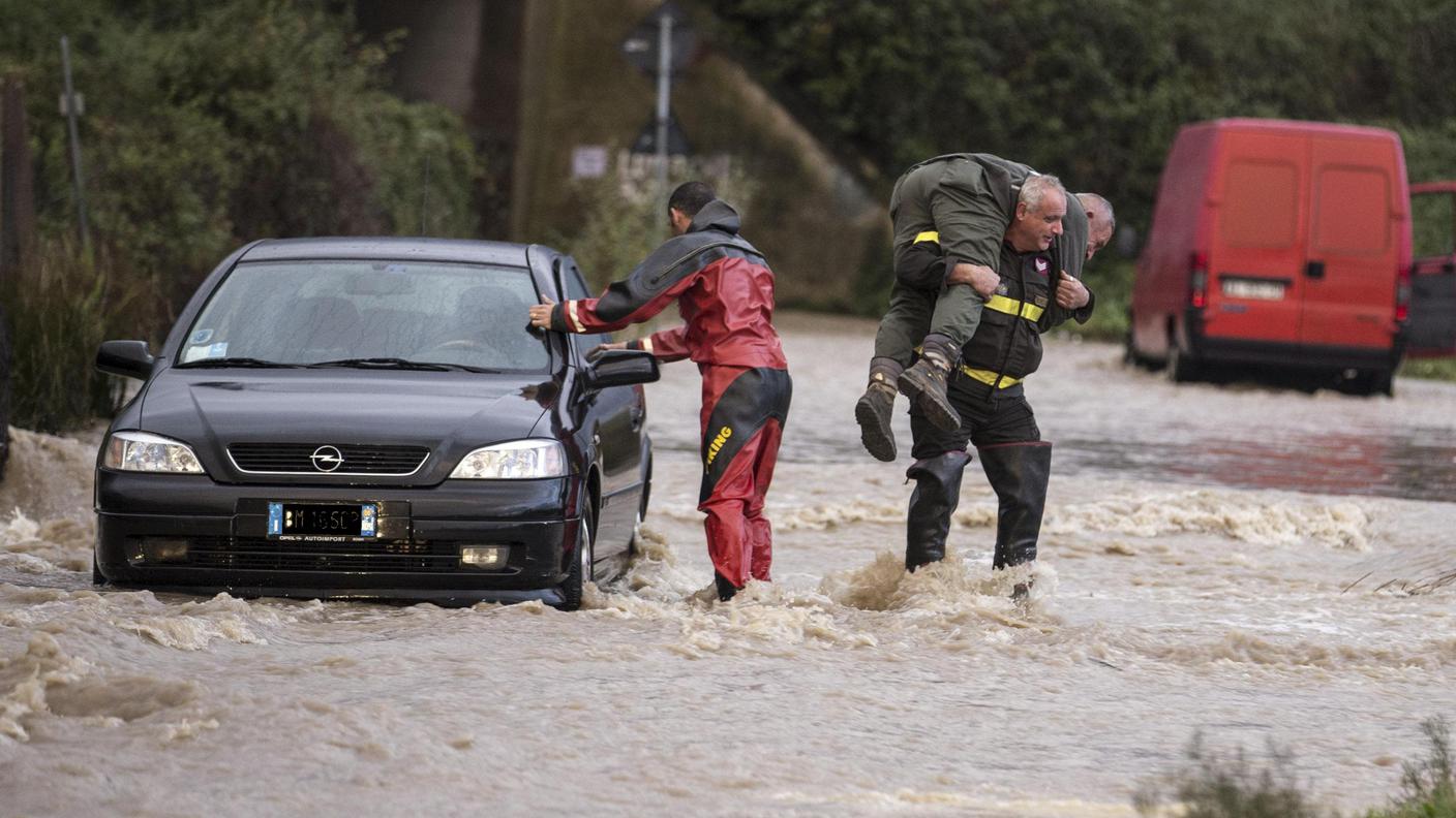 Soccorritori aiutano un automobilista in difficoltà sulla strada allagata