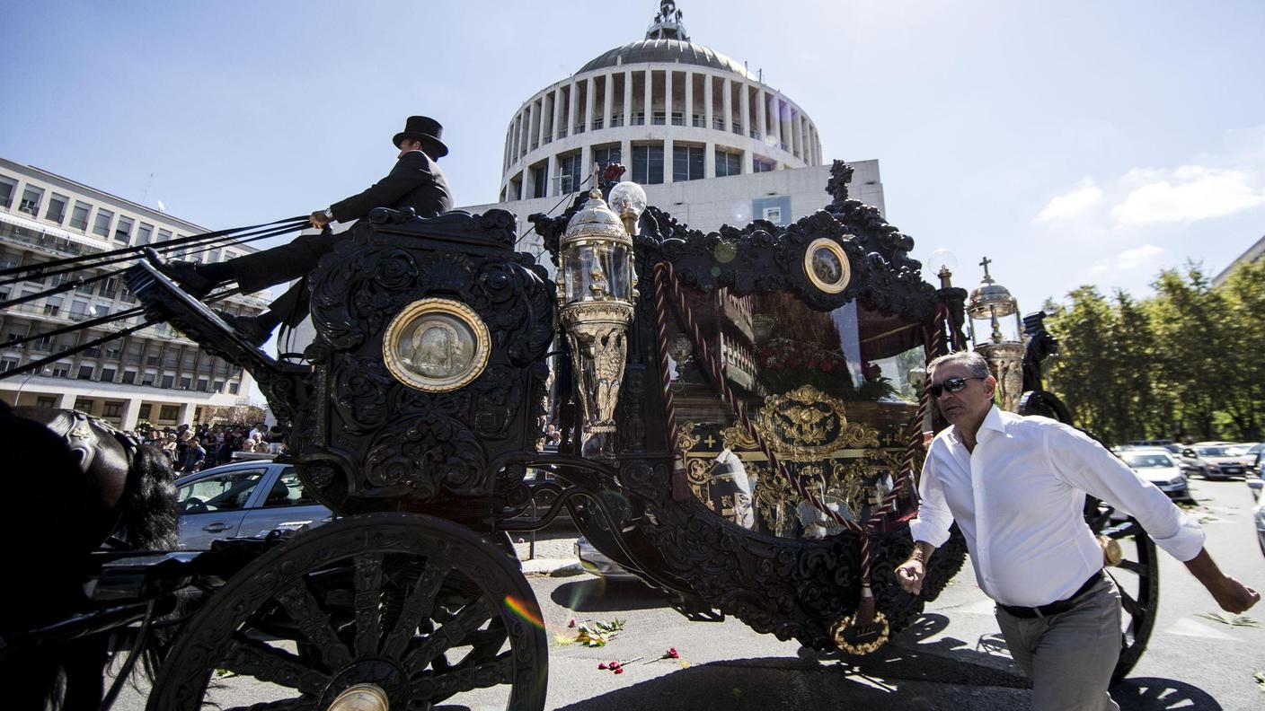 La carrozza funebre con i fregi dorati ed i cavalli neri davanti alla chiesa