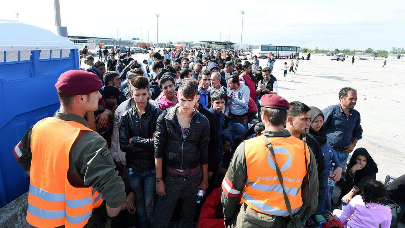Rifugiati attendono di attraversare la frontiera austriaca a Nickelsdorf