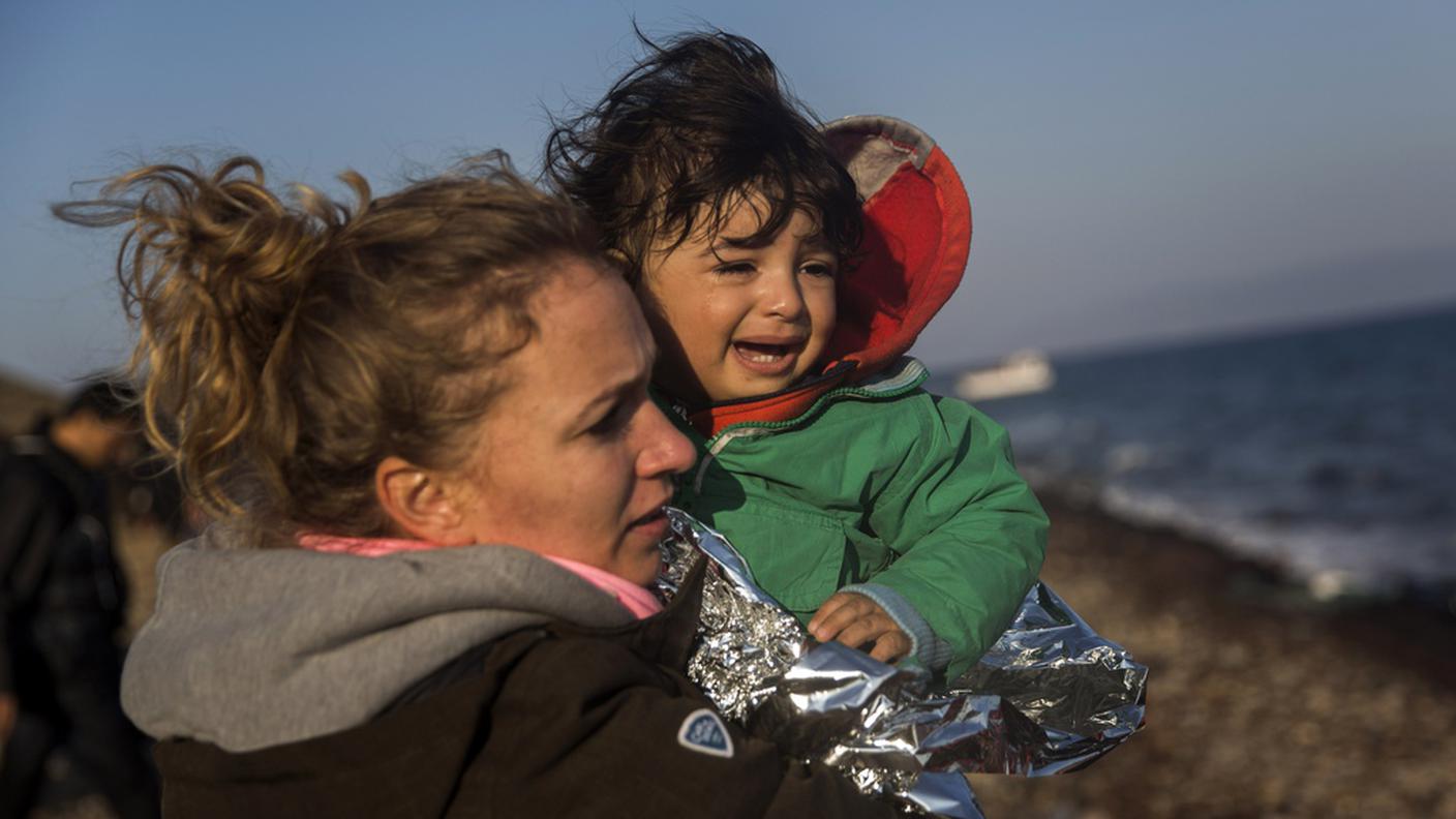 Una volontaria aiuta una bimba sull'isola greca di Lesbo
