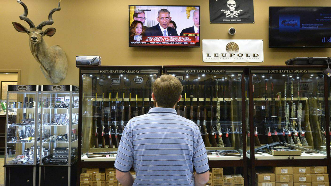 Un negozio di armi, sullo sfondo l'intervento di Obama contro la lobby dei produttori